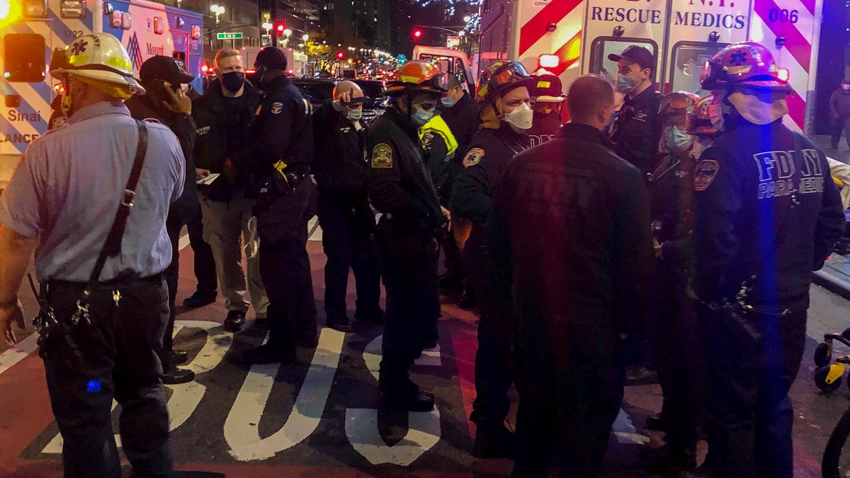 Emergency personnel at an intersection where pedestrians were struck by a car during a protest Friday, Dec. 11, 2020, in New York. The New York Fire Department says six people were hospitalized. (AP Photo/David Martin)