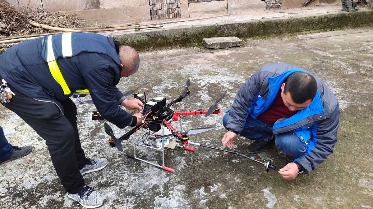 In this Dec. 10, 2020, photo released by Blue Sky Rescue of Zhong County, workers prepare a drone equipped with a flamethrower at a village near Chongqing municipality in southwestern China. (Blue Sky Rescue of Zhong County via AP)