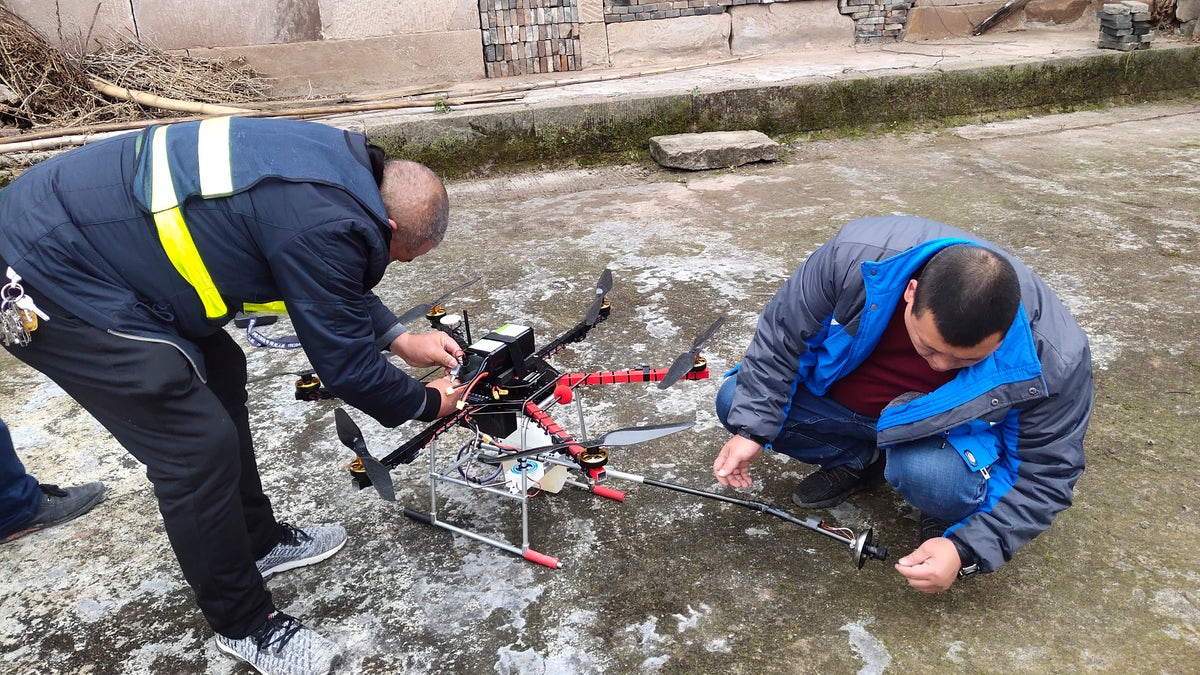 In this Dec. 10, 2020, photo released by Blue Sky Rescue of Zhong County, workers prepare a drone equipped with a flamethrower at a village near Chongqing municipality in southwestern China. (Blue Sky Rescue of Zhong County via AP)