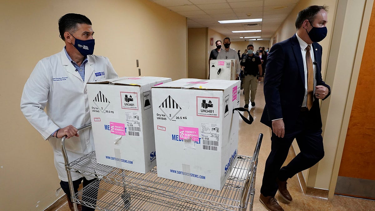 Ramon Docobo, left, assistant director of the Tampa General Hospital Pharmacy, wheels the COVID-19 vaccine into the pharmacy Monday, Dec. 14, 2020, at the hospital in Tampa, Fla. (AP Photo/Chris O'Meara)