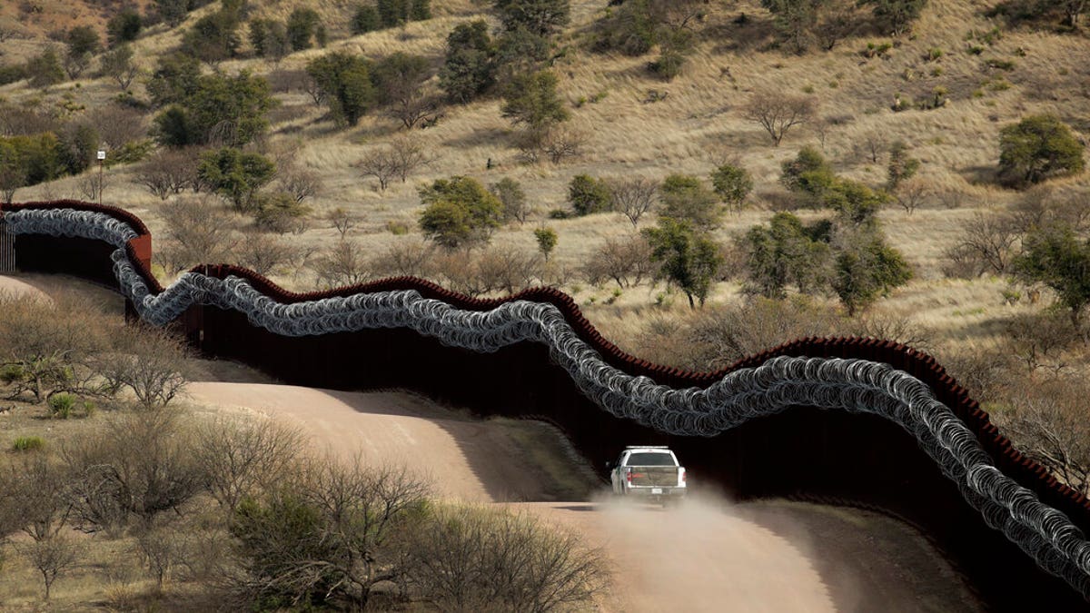 In this March 2, 2019 photo, a Customs and Border Control agent patrols on the U.S. side of a razor-wire-covered border wall along Mexico east of Nogales, Ariz. (AP Photo/Charlie Riedel, File)