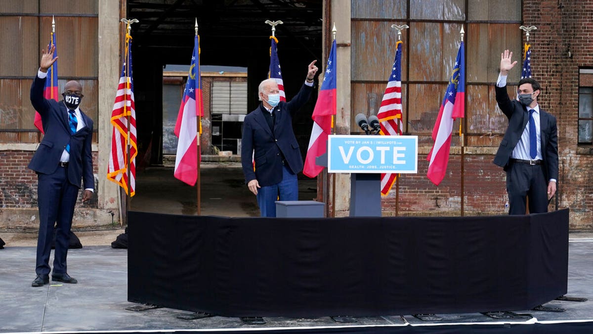 President-elect Joe Biden, center, acknowledges supporters at the end of a drive-in rally for Georgia Democratic candidates for U.S. Senate Raphael Warnock, left, and Jon Ossoff, Tuesday, Dec. 15, 2020, in Atlanta. (AP Photo/Patrick Semansky)