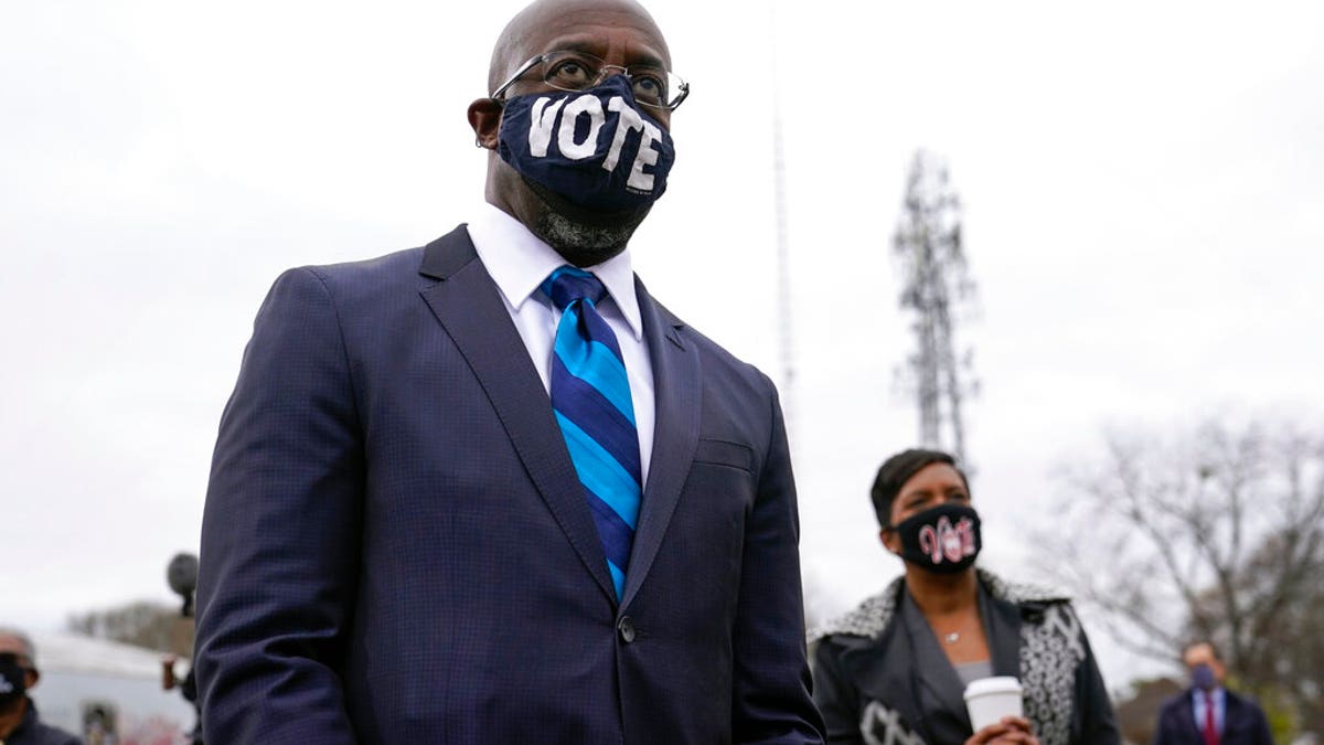 Georgia Democratic candidate for U.S. Senate Raphael Warnock listens as President-elect Joe Biden speaks at a drive-in rally for Warnock and Jon Ossoff, Dec. 15, in Atlanta. (AP Photo/Patrick Semansky)
