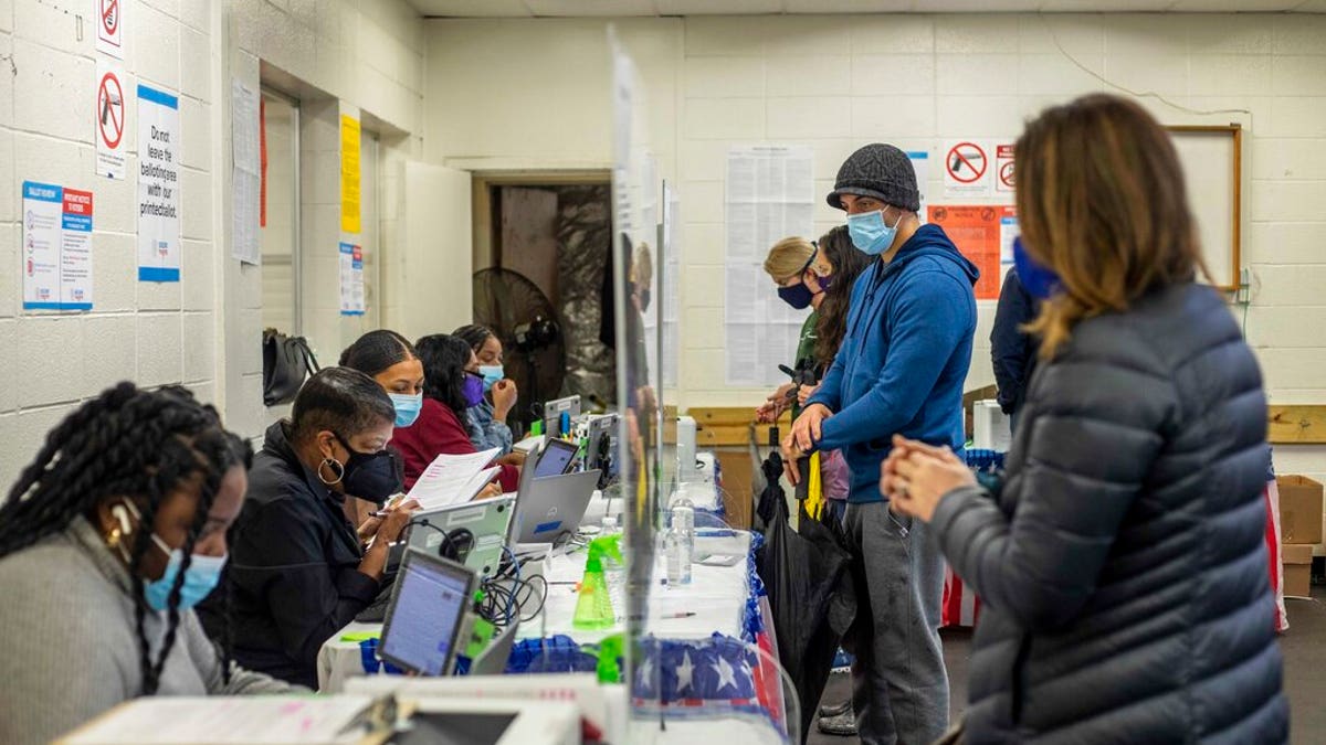 Fulton County elections workers work with voters during early voting in the state's runoff election at Chastain Park Gymnasium in Atlanta's Chastain Park neighborhood, Dec. 16, 2020. (Alyssa Pointer/Atlanta Journal-Constitution via AP)