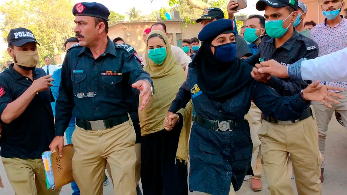 Police officers escort Arzoo Raja, center, a teenage Christian girl, who was allegedly abducted and forced to convert and marry a 44-year old Muslim, while they leave after an appearance before the High Court in Karachi, Pakistan, Nov. 3, 2020.  (AP Photo/Fareed Khan)