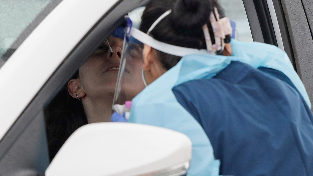 A woman receives a COVID-19 test at a drive through testing station at a beach in Sydney, Australia, Saturday, Dec. 19, 2020. Sydney's northern beaches will enter a lockdown similar to the one imposed during the start of the COVID-19 pandemic in March as a cluster of cases in the area increased to more than 40. (AP Photo/Mark Baker)