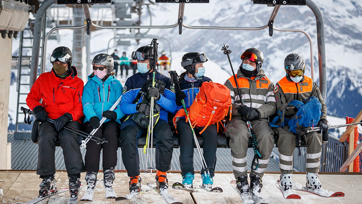 A policewoman and policeman (center) ride a ski lift as they patrol on the slopes and in alpine restaurants specifically, to check the application of sanitary measures during the coronavirus disease (COVID-19) outbreak, in the alpine resort of Villars-sur-Ollon, Switzerland, Saturday, December 19, 2020. The police receives local support of the "protection civile", civil protection (right), in alpine resort. (Valentin Flauraud/Keystone via AP)