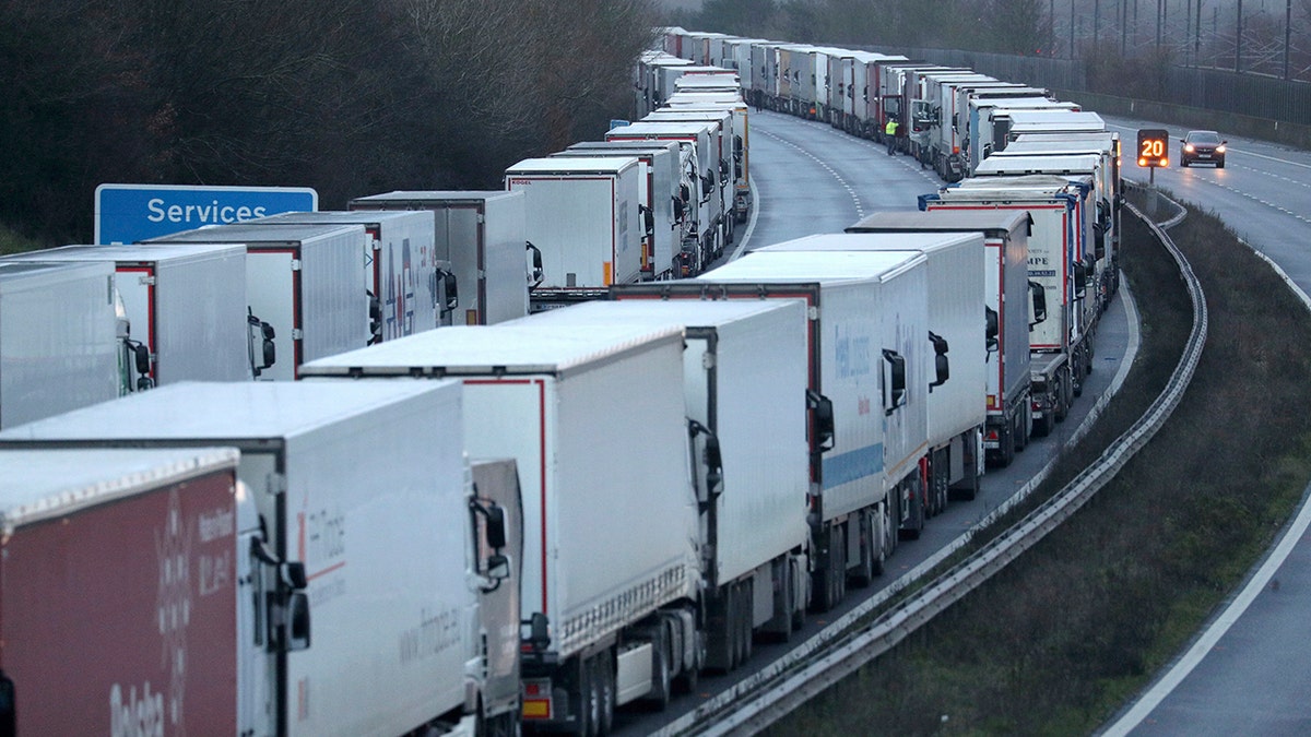Trucks are parked along the M20 motorway where freight traffic is halted whilst the Port of Dover remains closed, in Ashford, Kent, England, Tuesday, Dec. 22, 2020. Trucks waiting to get out of Britain backed up for miles and people were left stranded at airports as dozens of countries around the world slapped tough travel restrictions on the U.K. because of a new and seemingly more contagious strain of the coronavirus in England. (Andrew Matthews/PA via AP)