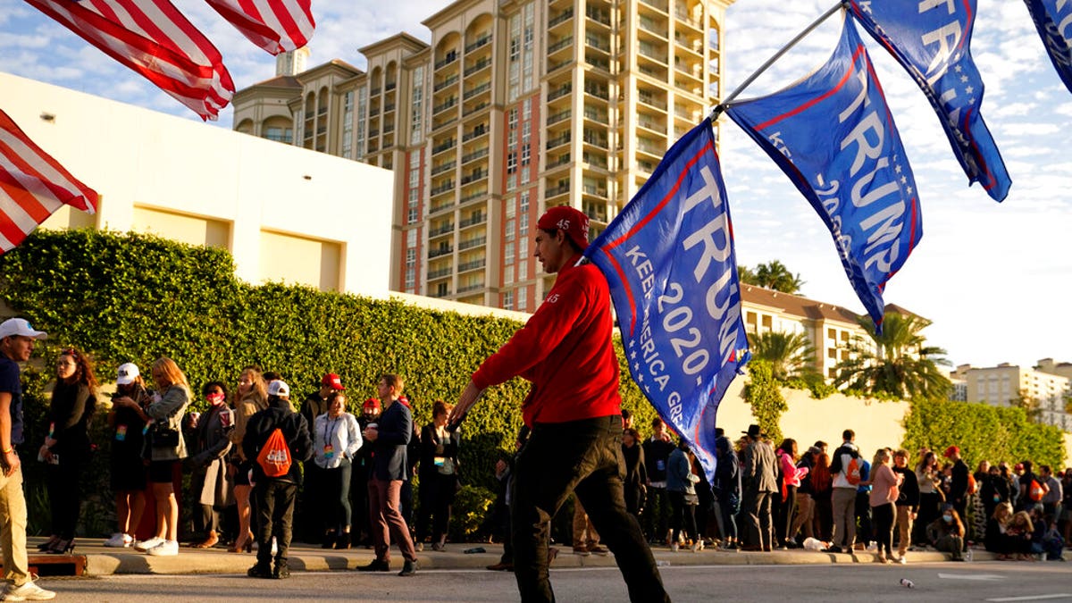Josh Platillero, of Knoxville, Tenn. skates with flags in support of President Trump as people wait for the doors to open outside of the Turning Point USA Student Action Summit, Tuesday, Dec. 22, 2020, in West Palm Beach, Fla. (AP Photo/Lynne Sladky)