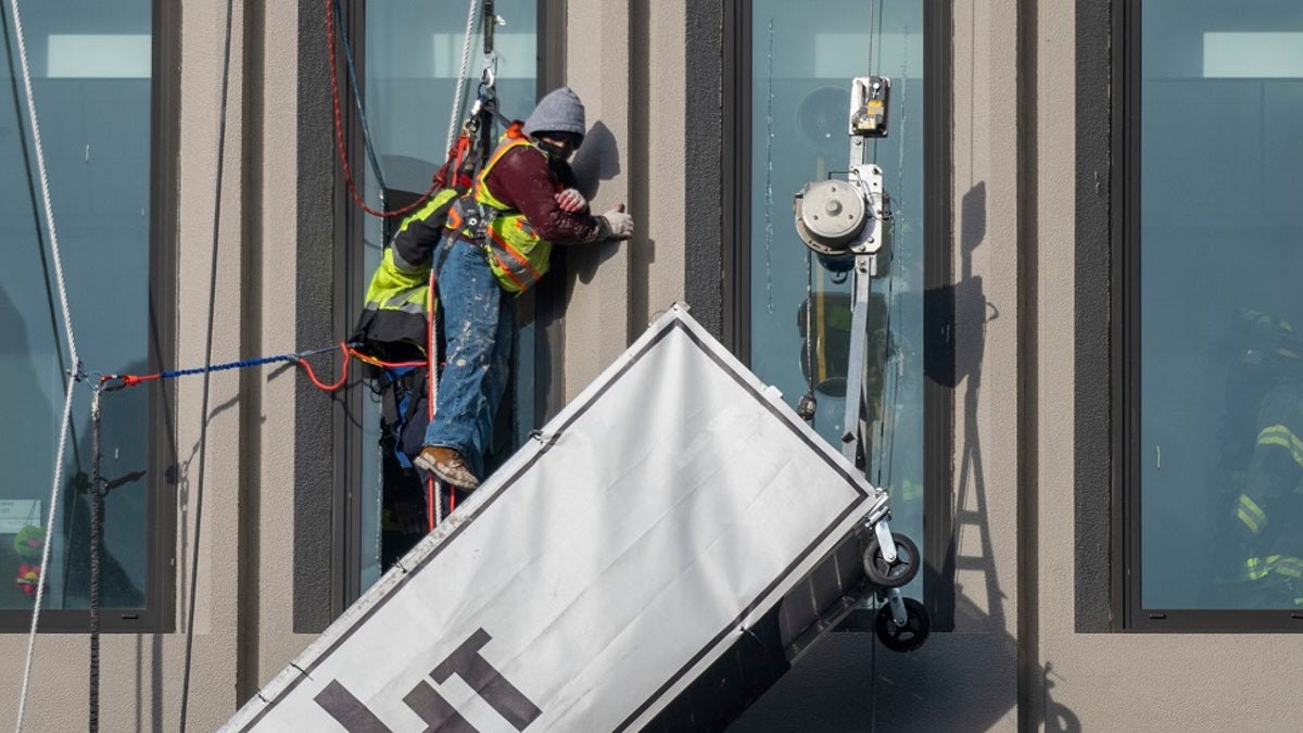 A worker stands on the end of a dangling scaffold as he waits to be rescued following an explosion at Baltimore Gas and Electric's offices, on Wednesday. Twenty-one of the victims were brought to area hospitals following the explosion with a partial roof collapse. The city’s fire department tweeted that at least nine of the victims were in critical condition, while another was in serious condition. (Jerry Jackson/The Baltimore Sun via AP)