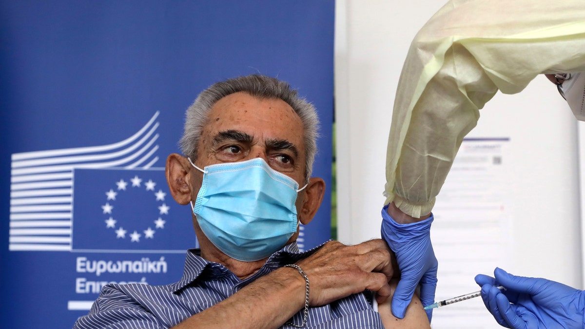 Andreas Raounas, 84, the first patient in Island receives from a nurse the vaccine of Pfizer BioNtech against the COVID-19, at a care home in Nicosia, Cyprus, Sunday, Dec. 27, 2020. Cyprus started today the vaccination program against COVID-19. (Katia Christodoulou/Pool Photo via AP)