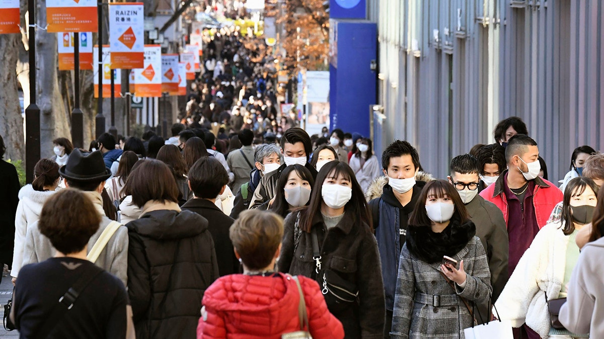 People wearing face masks to help curb the spread of the coronavirus walk on Aoyama shopping street in Tokyo Sunday, Dec. 27, 2020. Japan is barring entry of all nonresident foreign nationals as a precaution against a new and potentially more contagious coronavirus variant that has spread across Britain. The Foreign Ministry says the entry ban will start Monday and last through Jan. 31. (Yuka Ando/Kyodo News via AP)
