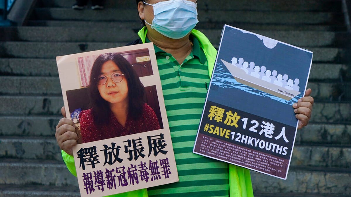 A pro-democracy activist holds placards with the picture of Chinese citizen journalist Zhang Zhan outside the Chinese central government's liaison office, in Hong Kong. (AP Photo/Kin Cheung)