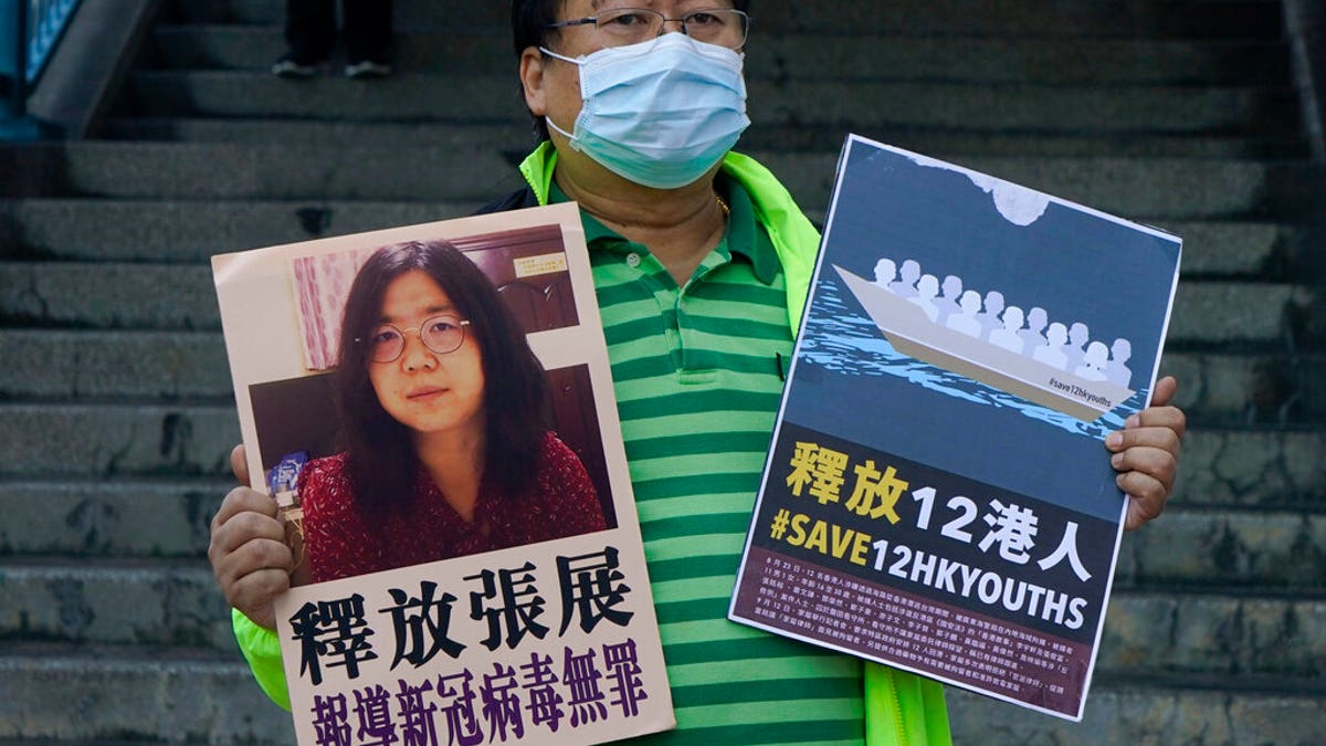 A pro-democracy activist holds placards with the picture of Chinese citizen journalist Zhang Zhan outside the Chinese central government's liaison office, in Hong Kong. (AP Photo/Kin Cheung)