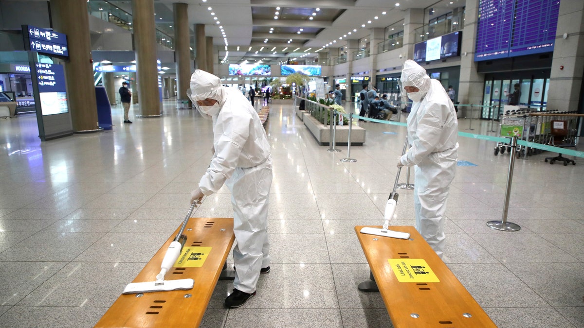 Workers wearing protective gears disinfect chairs as a precaution against the coronavirus at the arrival hall of the Incheon International Airport in Incheon, South Korea, Monday, Dec. 28, 2020. South Korea has confirmed its first cases of a more contagious variant of COVID-19 that was first identified in the United Kingdom. (Kim Sun-woong/Newsis via AP)