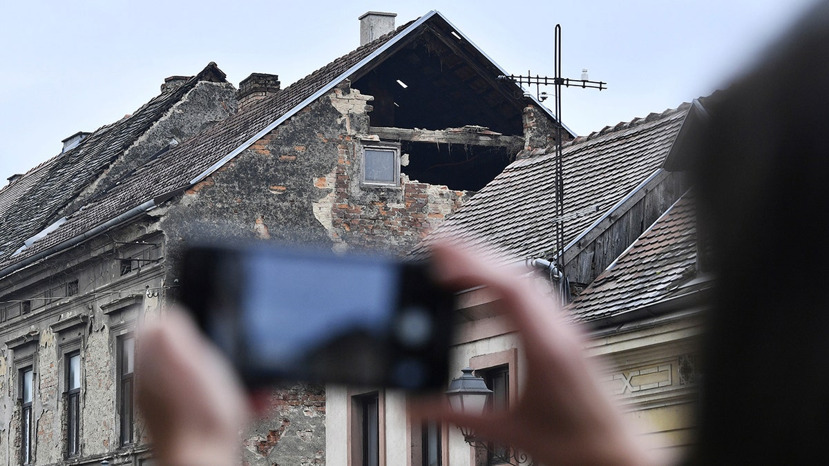 A resident takes a photograph of the damage caused by an earthquake in Sisak, Croatia, Monday, Dec. 28, 2020. A moderate earthquake has hit central Croatia near its capital of Zagreb, triggering panic and some damage south of the city. There were no immediate reports of injuries. (AP Photo)