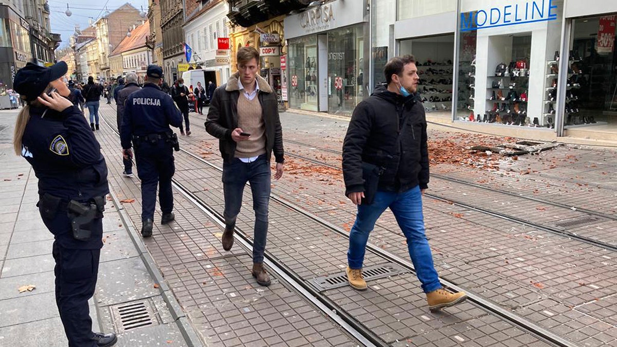 Residents walk past debris caused by an earthquake in downtown Zagreb, Croatia, Tuesday, Dec. 29, 2020. A strong earthquake hit Croatia on Tuesday, with some injuries reported as well as considerable damage to roofs and buildings southeast of the capital. (AP Photo/Filip Horvat)