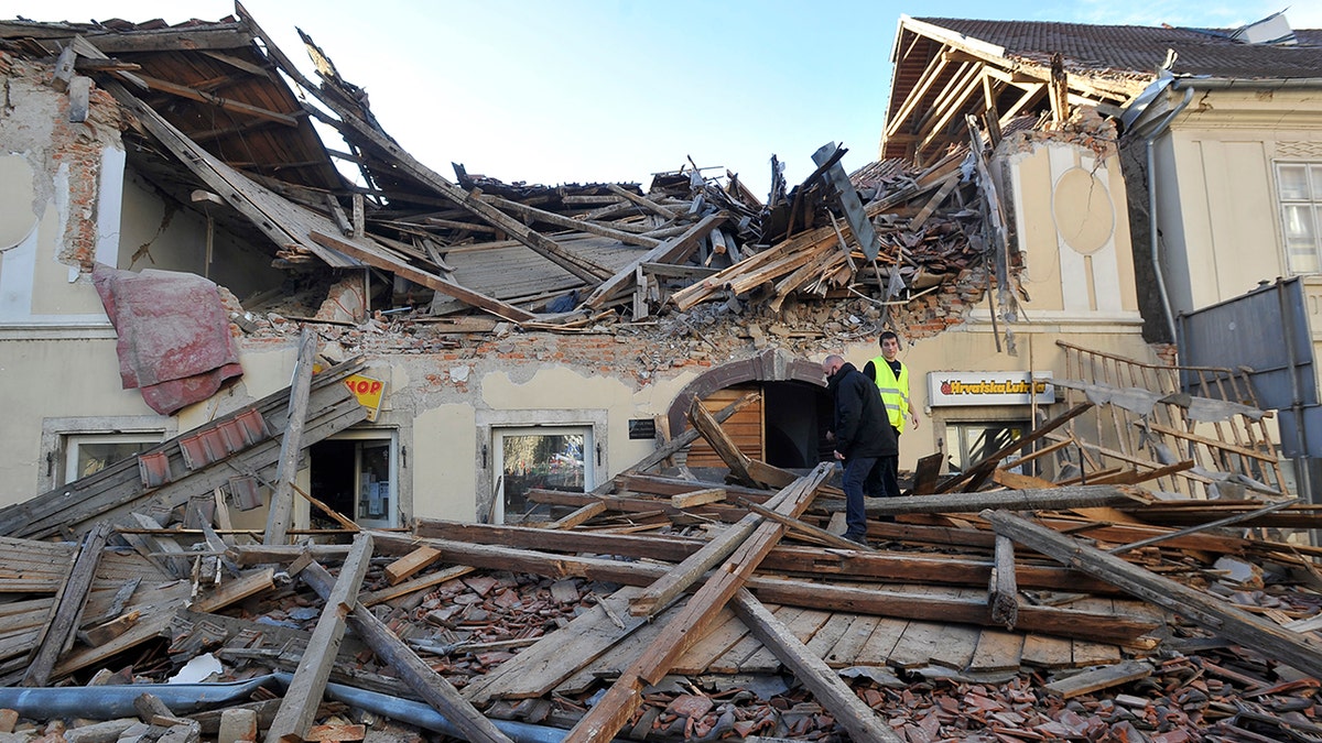 People walk through the rubble from buildings damaged in an earthquake in Petrinja, Croatia, Tuesday, Dec. 29, 2020. A strong earthquake has hit central Croatia and caused major damage and at least one death and some 20 injuries in the town southeast of the capital Zagreb. (AP Photo)