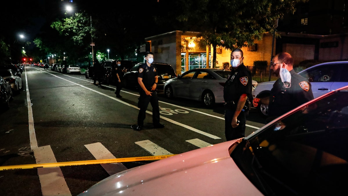 In this July 18, 2020, file photo, police officers respond to a crime scene were two individuals were shot on Atlantic Avenue in the Brooklyn borough of New York. Heralded as the safest big city in America in recent years, New York City is closing out its bloodiest year in nearly a decade. (AP Photo/John Minchillo, File)