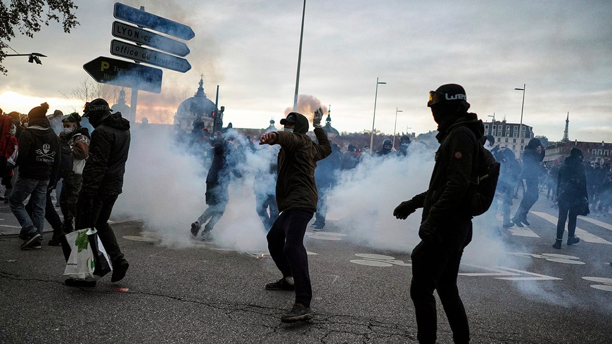 A man throws a bottle at the police during a demonstration in Lyon, central France, Dec. 5. Thousands marched in protests around France on Saturday against a contested security bill with tensions quickly rising at the Paris march as intruders set fire to several cars, broke windows and tossed objects at police. (AP Photo/Laurent Cipriani)