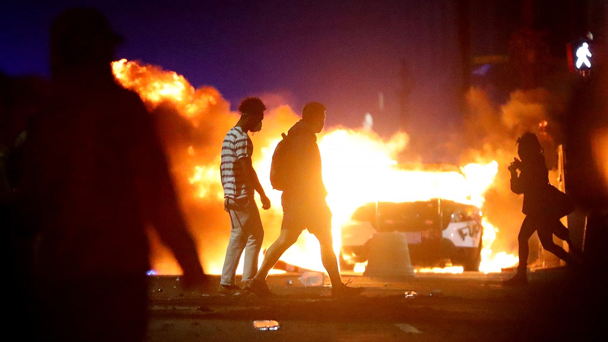 Demonstrators walk in front of a police car that has been lit on fire during a protest in response to the recent death of George Floyd on May 31, 2020 in Boston, Massachusetts. Protests spread across cities in the U.S., and in other parts of the world in response to the death of African American George Floyd while in police custody in Minneapolis, Minnesota. (Photo by Maddie Meyer/Getty Images)