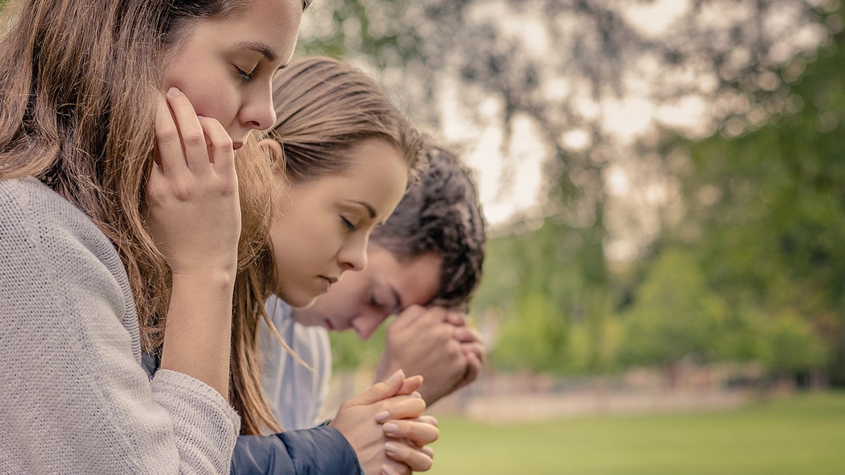 Kids praying outside with hands folded