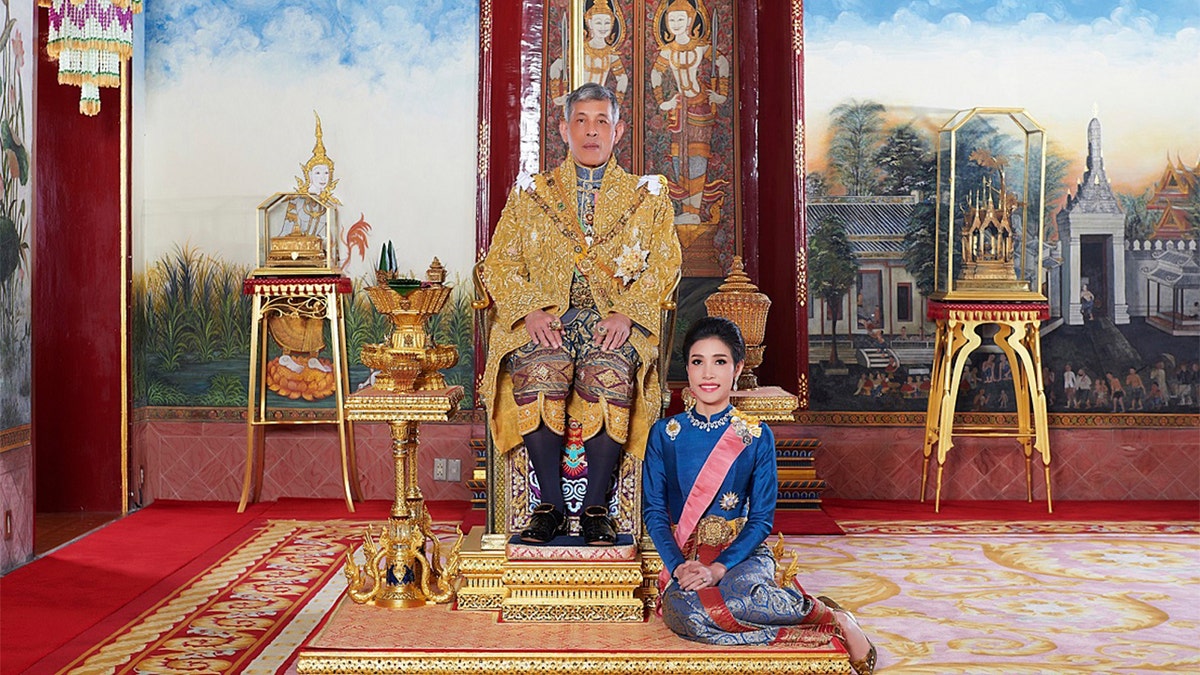 In this undated photo posted in 2019, on the Thailand Royal Office website, Thailand's King Maha Vajiralongkorn sits on the throne with his official consort Sineenatra Wongvajirabhakdi at the royal palace. (Thailand Royal Office via AP)