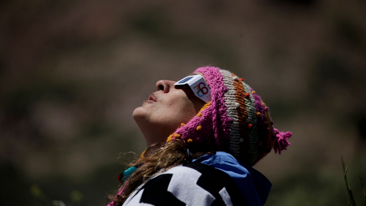 A woman wears special glasses to watch a total solar eclipse in Piedra del Aguila, Argentina, Monday, Dec. 14, 2020.