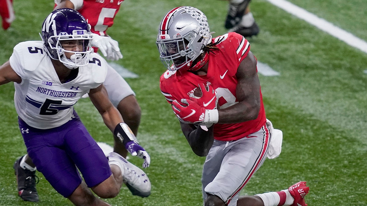 Ohio State running back Trey Sermon, right, scores past Northwestern defensive back JR Pace (5) during the second half of the Big Ten championship NCAA college football game, Saturday, Dec. 19, 2020, in Indianapolis. (AP Photo/Darron Cummings)