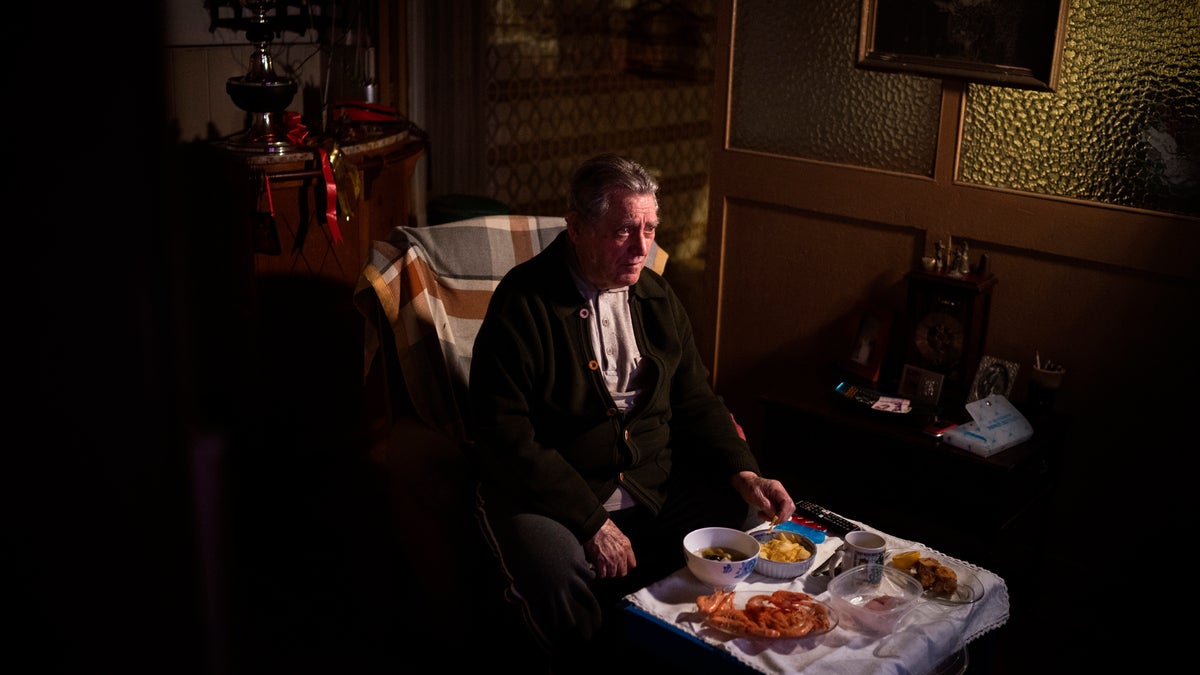 Álvaro Puig Moreno watches television while eating a his Christmas Eve dinner at his home in Barcelona, Spain, Thursday, Dec. 24, 2020. "The solitude gets to me these days, I often feel depressed," Puig said. "These holidays, instead of making me happy, make me sad. I hate them. Most of family has died, I am one of the last ones left. I will spend Christmas at home alone because I don't have anyone to spend them with."