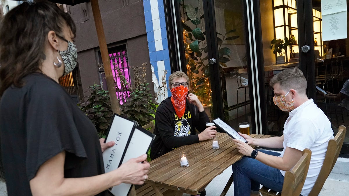 In this Sept. 29 photo, restaurant owner Samantha DiStefano, left, of Mama Fox, prepares to hand menus to patrons dining outside at her Brooklyn establishment, in New York. (AP Photo/Kathy Willens, File)