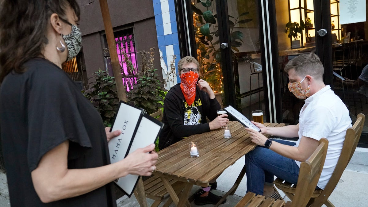 In this Sept. 29 photo, restaurant owner Samantha DiStefano, left, of Mama Fox, prepares to hand menus to patrons dining outside at her Brooklyn establishment, in New York. (AP Photo/Kathy Willens, File)