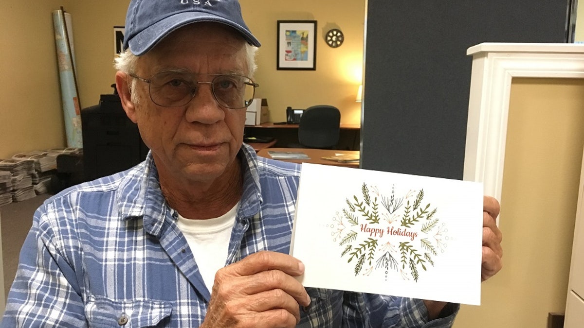 Mike Esmond holds a holiday card in 2019 informing customers in Gulf Breeze, Fla., that their past due utility bills have been paid.
