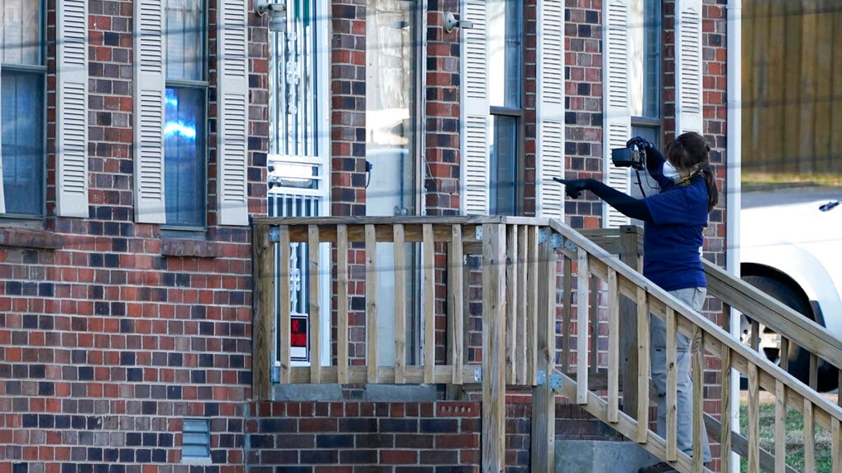A member of the FBI Evidence Response Team photographs the entrance of a home Saturday, Dec. 26, 2020, in Nashville, Tenn. An explosion that shook the largely deserted streets of downtown Nashville early Christmas morning shattered windows, damaged buildings, and wounded three people. Authorities said they believed the blast was intentional. (AP Photo/Mark Humphrey)