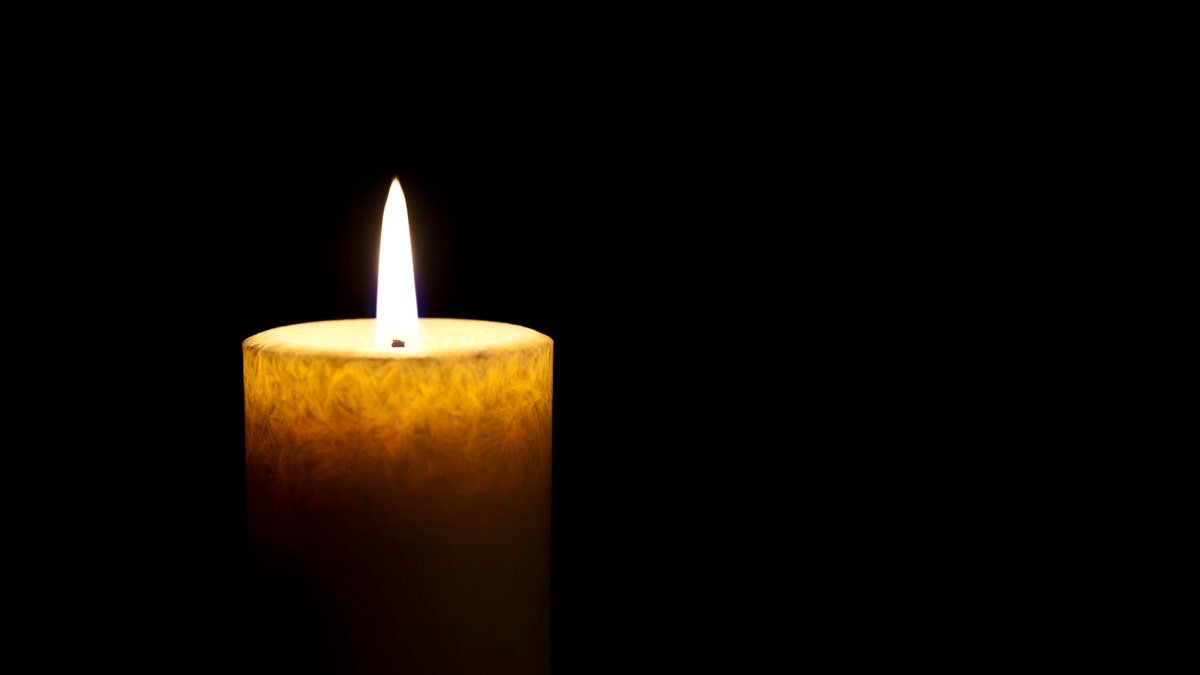 single lit candle in darkness