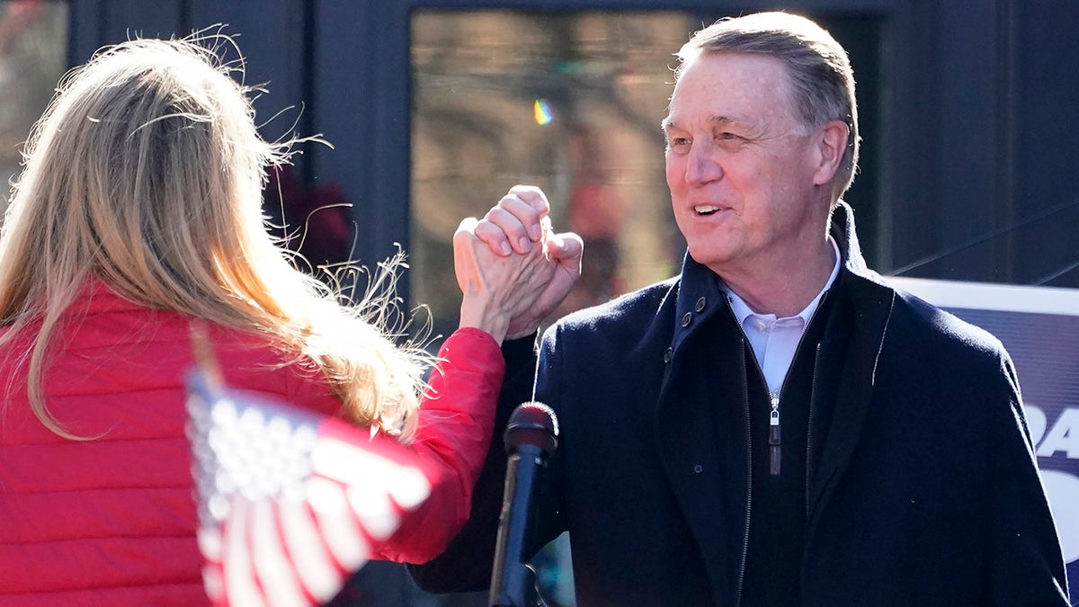 Sen. David Perdue, R-Ga., and Sen. Kelly Loeffler, R-Ga., clasp hands during a campaign rally, Monday Dec. 21, 2020, in Milton, Ga. (AP Photo/John Bazemore)