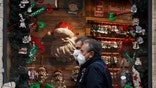 People walk past a shop window adorned with Christmas decorations, in Rome Tuesday, Dec. 1, 2020. Still, the large number of daily new COVID-19 cases is worrying, Italian health experts said, especially with the approach of year-end holidays, which could prompt people to ignore social distancing rules and gather in large numbers to celebrate. (AP Photo/Gregorio Borgia)