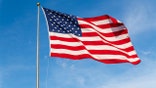 American Flag waving in the wind, with beautiful red white and blue colors.