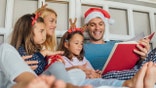 Young couple reading a book while resting with children