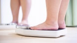 plus size asian girl look mirror and measure her weight by scale