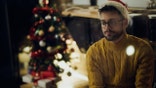 Young pensive man feeling lonely while spending New Year's eve alone at home.