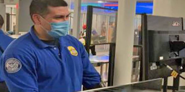 A Transportation Security Administration officer stands at an airport checkpoint. On Thursday, the TSA asked passengers to act calm and respectful at checkpoints amid a series of incidents involving unruly passengers. 