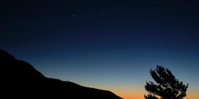 Saturn, top, and Jupiter, below, are seen after sunset from Shenandoah National Park, Sunday, Dec. 13, 2020, in Luray, Virginia. The two planets are drawing closer to each other in the sky as they head towards a "great conjunction" on December 21, where the two giant planets will appear a tenth of a degree apart. Photo Credit: (NASA/Bill Ingalls)