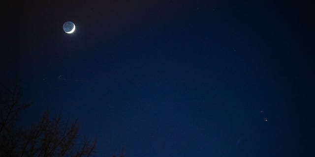 The Moon, left, Saturn, upper right, and Jupiter, lower right, are seen after sunset from Washington, DC, Thurs. Dec. 17, 2020. The two planets are drawing closer to each other in the sky as they head towards a "great conjunction" on December 21, where the two giant planets will appear a tenth of a degree apart. Photo Credit: (NASA/Aubrey Gemignani)