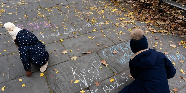 Students chalk graffiti on a sidewalk in front of New York's City Hall during a protest by parents and students opposing the closing of schools, Thursday, Nov. 19, 2020. (AP Photo/Mark Lennihan)