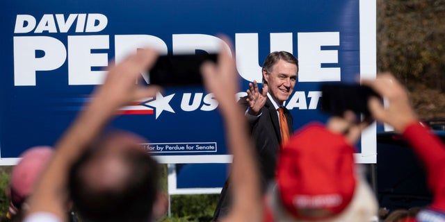 In this Nov. 20, 2020, file photo Sen. David Perdue, R-Ga., takes the stage before Vice President Mike Pence during a Defend the Majority Rally in Canton, Ga. (AP Photo/Ben Gray)