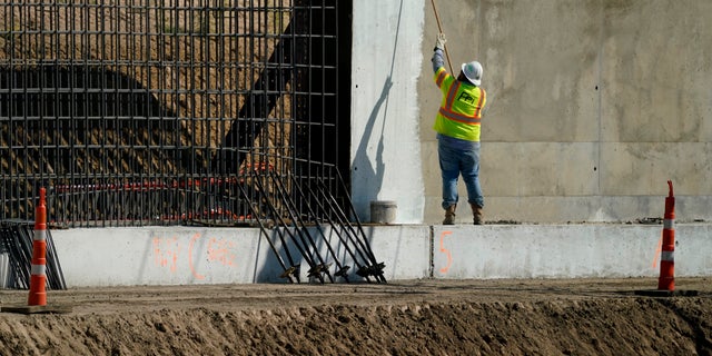 A construction worker paints part of a border wall in Mission, Texas on Monday, November 16, 2020. President-elect Joe Biden will face immediate pressure to keep his promise to stop construction of the border wall.  (AP Photo / Eric Gay)