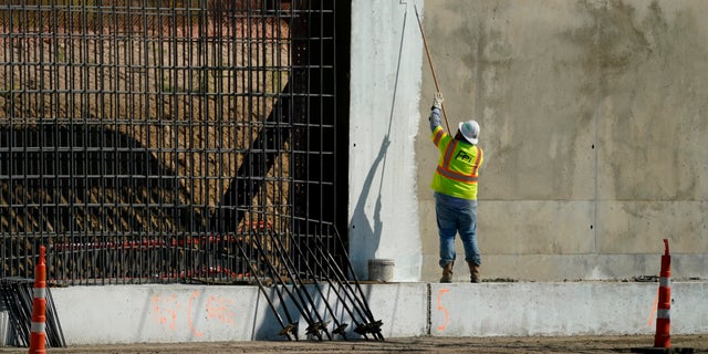 A construction worker paints part of a border wall in Mission, Texas on Monday, November 16, 2020. President-elect Joe Biden will face immediate pressure to keep his promise to stop construction of the border wall.  (AP Photo / Eric Gay)