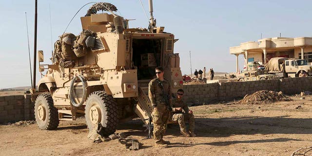 In this Feb. 23, 2017 file photo, U.S. Army soldiers stand outside their armored vehicle on a joint base with the Iraqi army, south of Mosul, Iraq. In a quest to root out Islamic State group hideouts over the summer, Iraqi forces on the ground cleared nearly 90 villages across a notoriously unruly northern province. But the much-touted operation still relied heavily on U.S. intelligence, coalition flights and planning assistance. (AP Photo/ Khalid Mohammed, File)