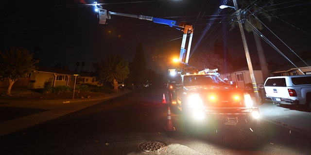 In this archive photo from October 25, 2020, debris flies through the air as a PG & amp; lineman  E works repairing electrical wires that were touching each other due to high winds on Manzanita Court in Concord, Calif. (Jose Carlos Fajardo / Bay Area News Group via AP, file)